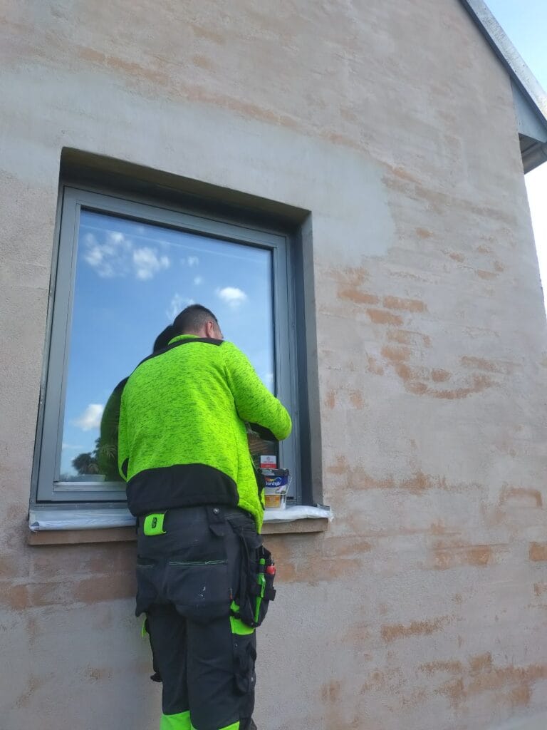 Målare arbetar med målning av fönsterkarm på villa i Malmö.